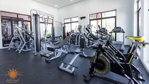 Et fitnesscenter med forskellig træningsudstyr, store vinduer og udsigt over det blå.