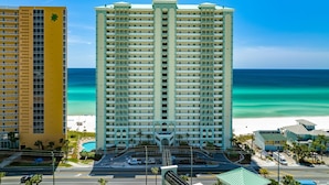 Un hotel de gran altura con varios balcones, una zona de piscina y vistas a la playa.