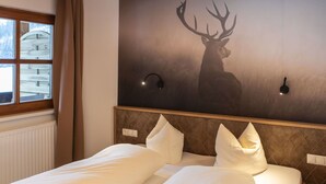 A hotel room with a large bed, a headboard with a diamond pattern, two wall sconces, and a window with curtains. - Cosy apartment for 4 guests with WIFI, TV, balcony and pets allowed (Vergötschen)