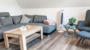 Un salon moderne avec une table basse en bois, un canapé gris à motifs et un fauteuil bleu.