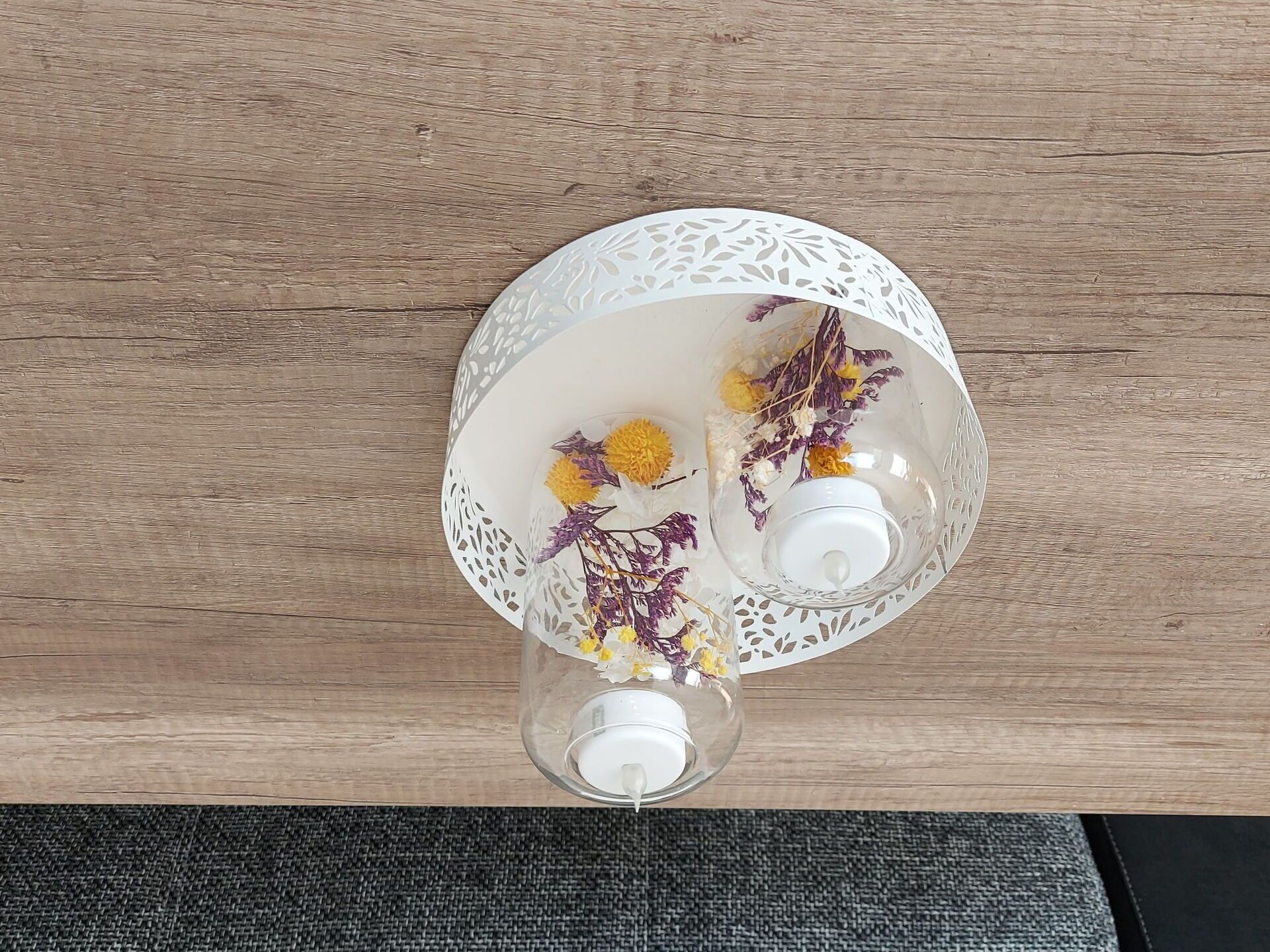Un jarrón de vidrio transparente con flores secas sobre una superficie de madera.