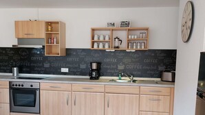 Une cuisine moderne avec des meubles en bois, un coin café et un tableau noir sur lequel sont écrits des mots liés au café.