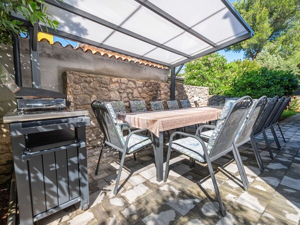 Un patio al aire libre con una parrilla, una mesa y sillas.