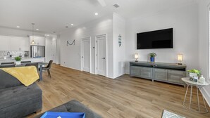 Ein modernes Wohnzimmer mit einem grauen Sofa, einem Couchtisch und einem an der Wand befestigten Fernseher.