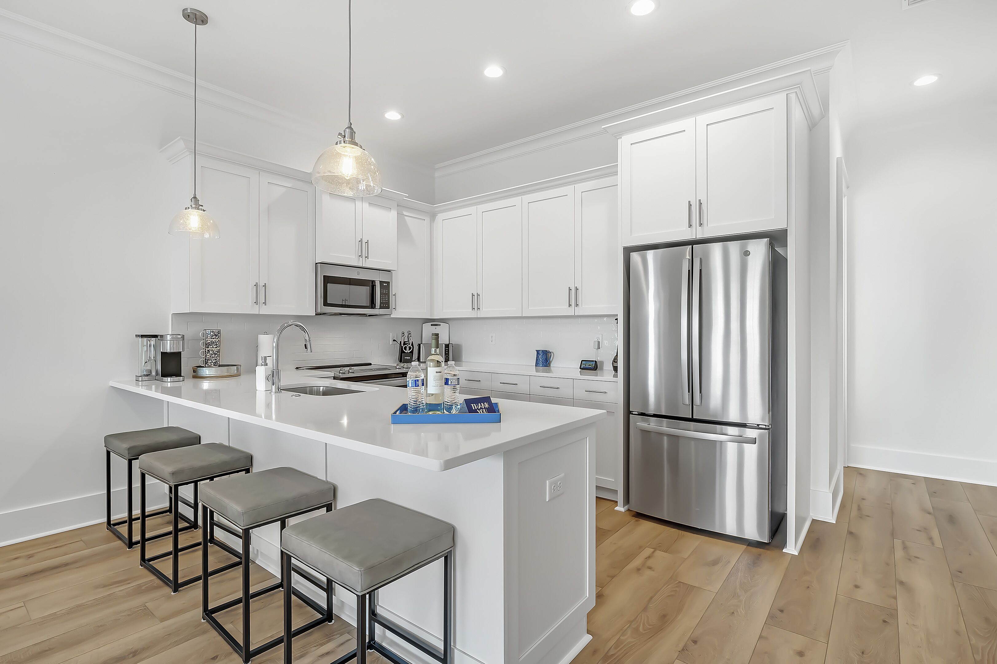 A modern kitchen with white cabinets, stainless steel appliances, and a central island with bar stools.