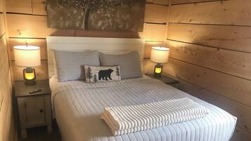A neatly made bed with a quilted duvet, two bedside lamps, and a nightstand with a remote control.