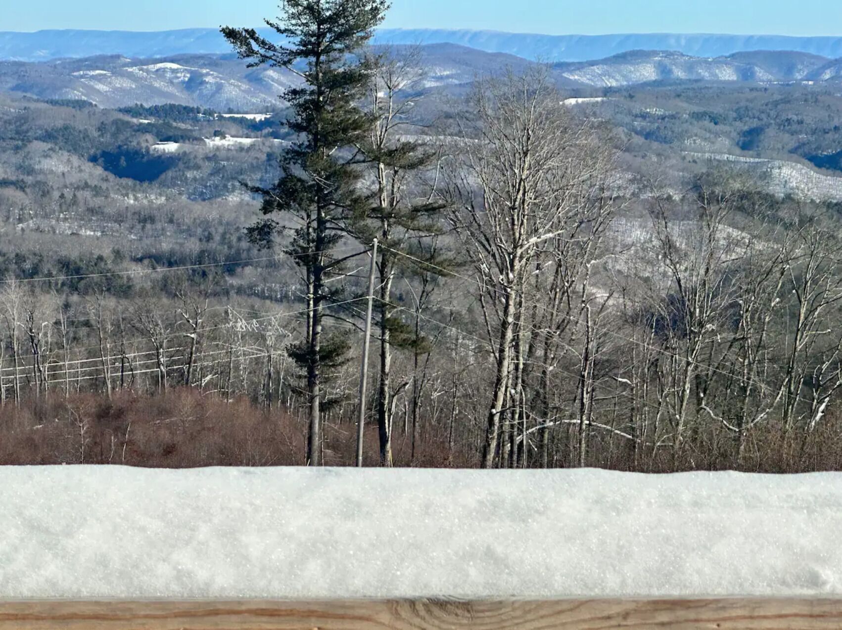 A snowy landscape with a forest and mountains in the background.