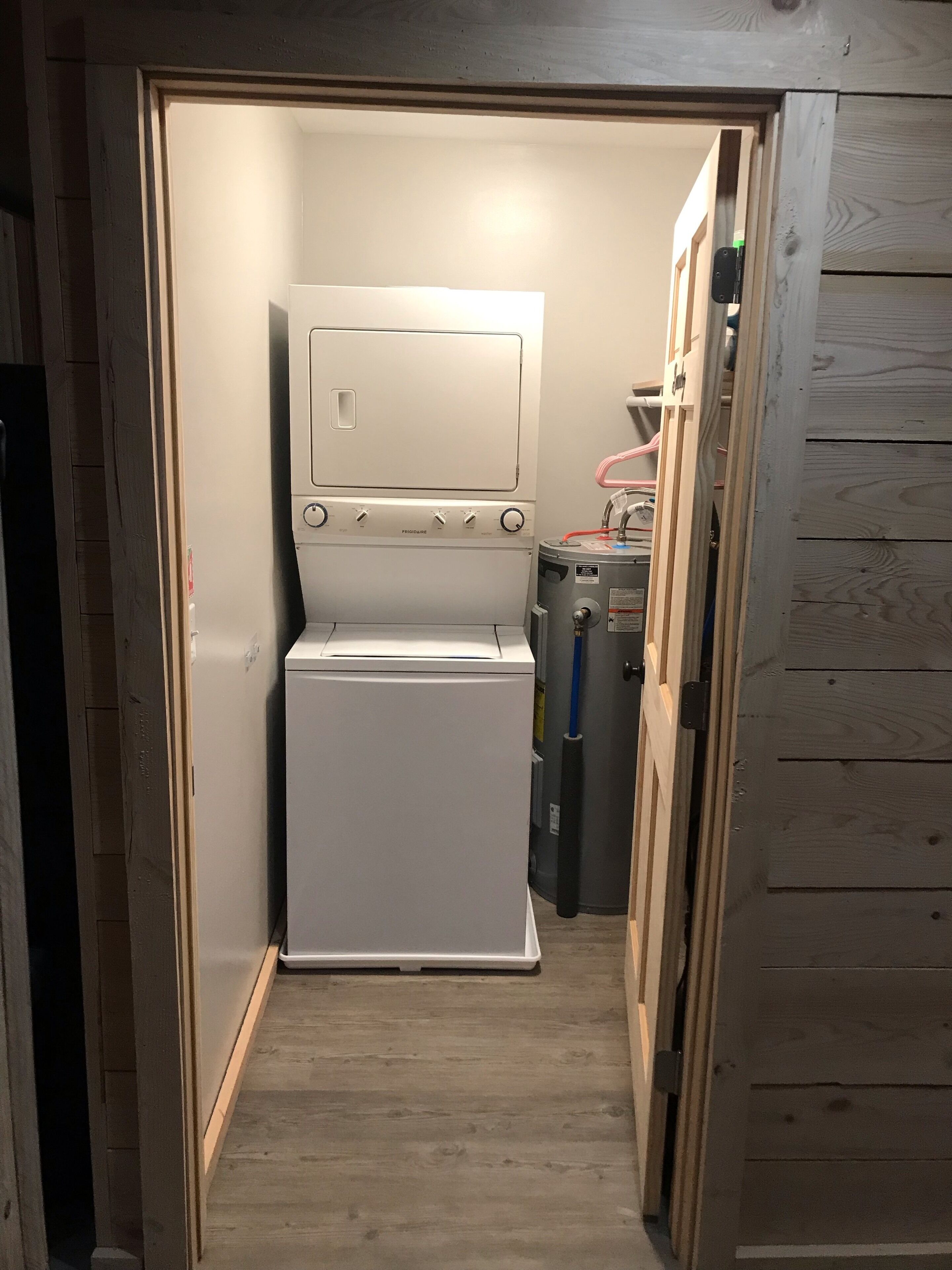 A compact laundry room with a white washer and dryer, a small heater, and a metal cabinet.