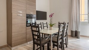 A modern kitchen with built-in appliances, a dining table with chairs, and a potted plant. - Apartments Florence - Pellicceria (sx) (Firenze)