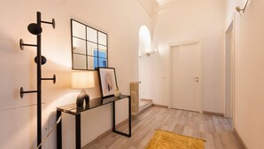 A hallway with a black console table, a lamp, a framed picture, a radiator, and a door. - Apartments Florence - Pellicceria (sx) (Firenze)