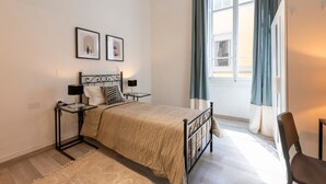 A bedroom with a bed, bedside tables, a window with curtains, and framed pictures on the wall. - Apartments Florence - Pellicceria (sx) (Firenze)