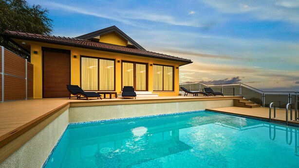 Un hôtel moderne doté d’une piscine, de chaises longues et d’une terrasse offrant une vue sur le ciel.