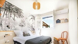 A bedroom with a bed, a chair, a wall-mounted shelf, and a window with a view of the outside. - Villa Oneway with swimming pool - Rated 3 stars ⭐⭐⭐ (Sainte-Rose)