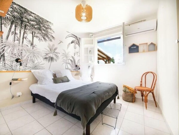 A bedroom with a bed, a chair, a wall-mounted shelf, and a window with a view of the outside.