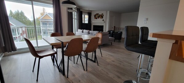 A modern living room with a dining area, a sofa, and a fireplace.