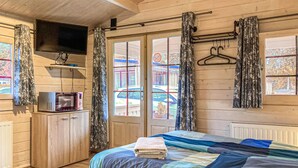 A bedroom with a bed, a TV mounted on the wall, a microwave, and a window with curtains. - Awesome home in Heinkenszand with WiFi (Heinkenszand)