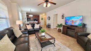 A living room with a leather sofa, a coffee table, a TV, and a fireplace.