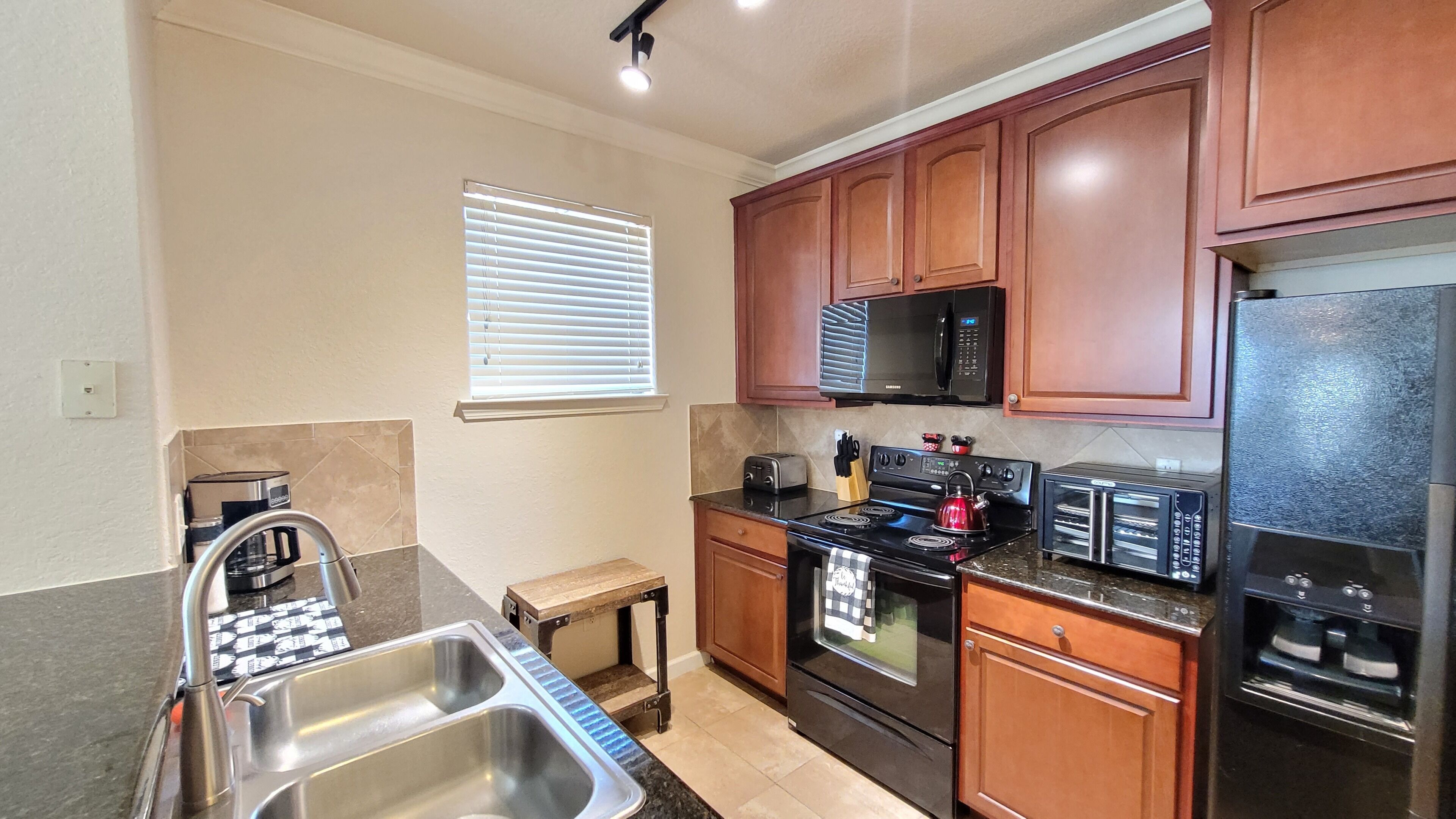 A kitchen with wooden cabinets, a microwave, a stove, a toaster, and a sink.
