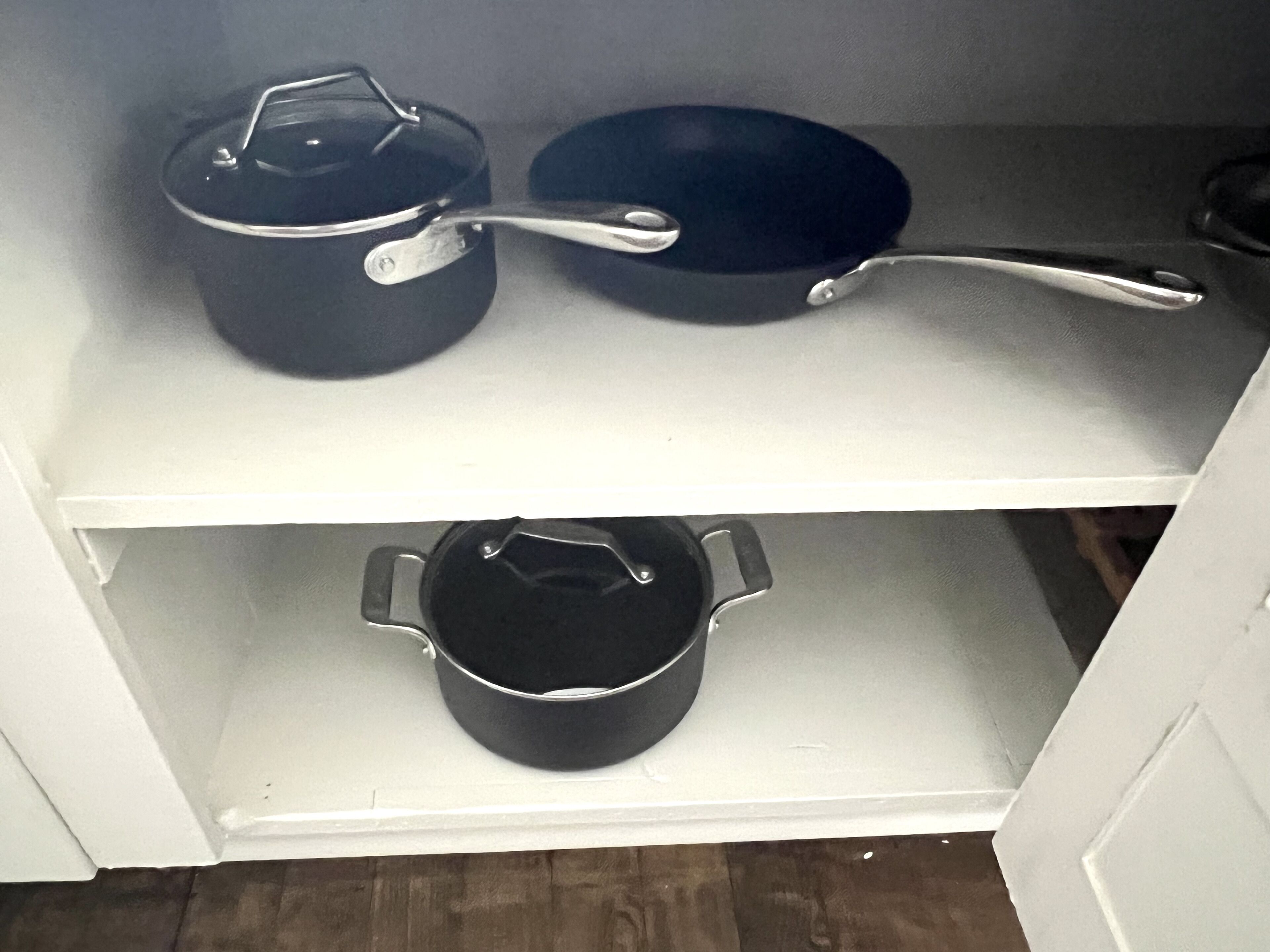 Una estantería de cocina con dos ollas y una sartén.