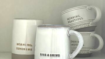 Three white ceramic mugs with handles, each featuring motivational phrases.