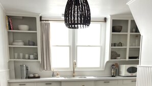 Una cocina con armarios blancos, una mesa de comedor de madera y una silla negra.
