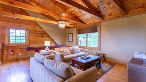A cozy cabin interior with a wooden ceiling, a sofa, a coffee table, and a fireplace. - Good Medicine - 10 minutes to Boone! Long range views, hot tub, fire pit! (Boone)