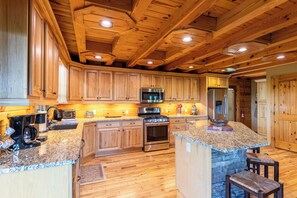 Una cocina amplia con armarios de madera, encimeras de granito, una isla central y electrodomésticos integrados.