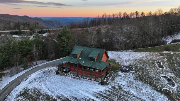 Une cabane dotée d’un toit végétalisé, entourée d’un paysage enneigé et bordée d’une forêt.