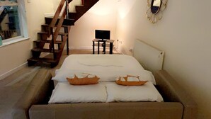 Een slaapkamer met een bed, een tafeltje, een televisie en een trap.