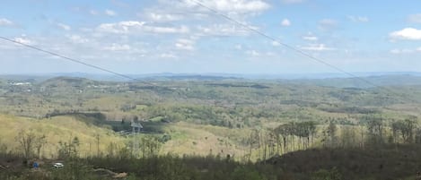 Vista panorámica de un paisaje montañoso con una línea eléctrica, un edificio pequeño y vegetación escasa.