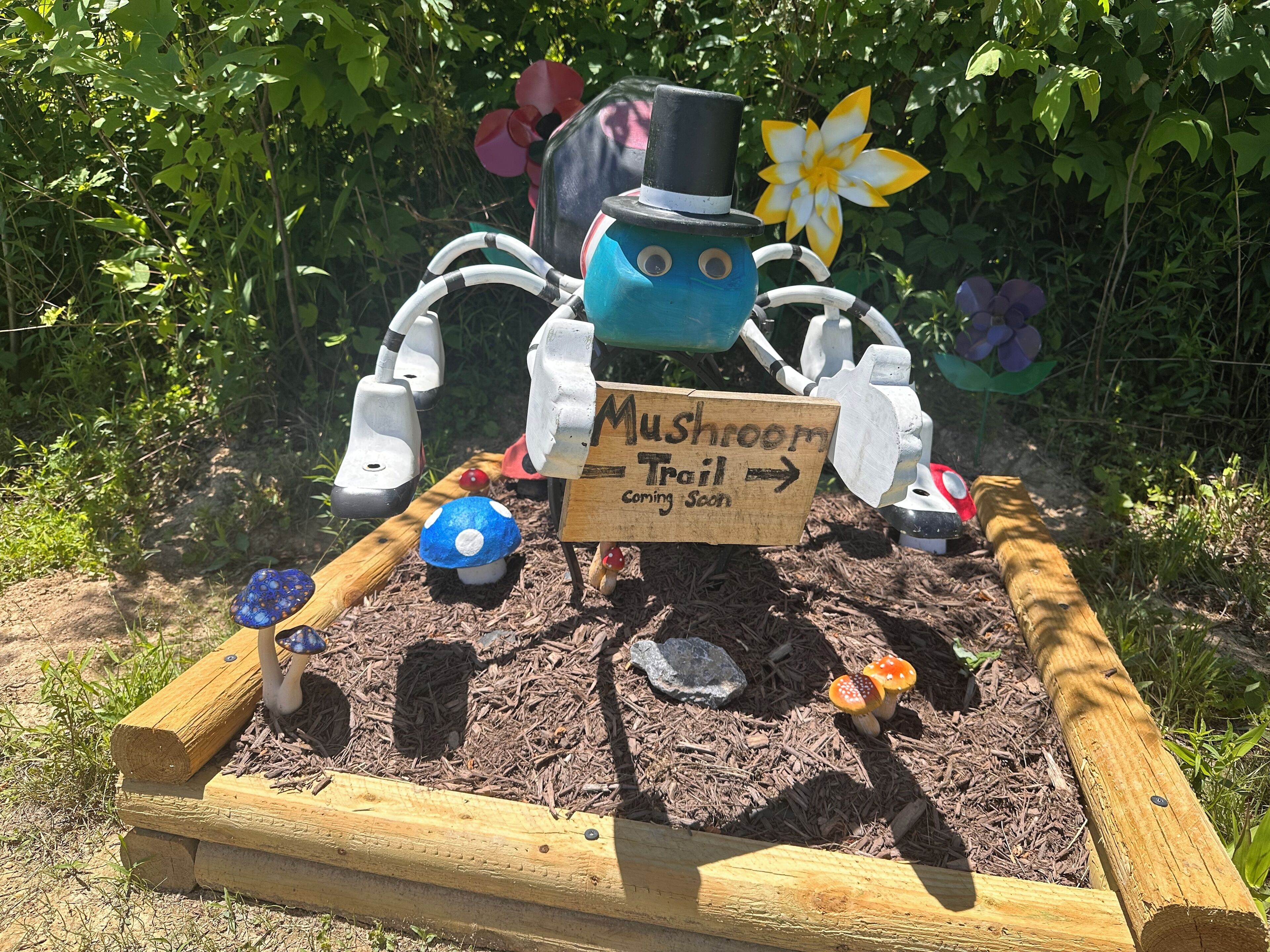 A garden display with a mushroom-themed sign and a mushroom figure.