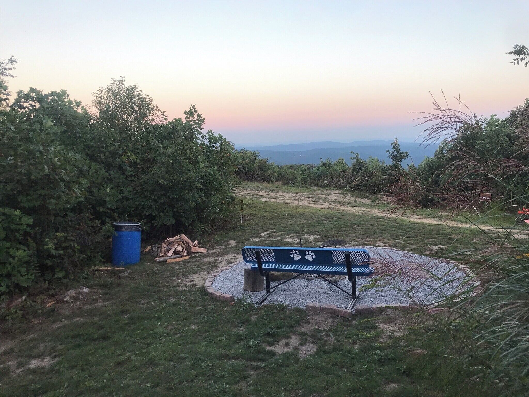 Un banco en una zona verde con vistas a montañas distantes.