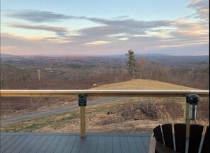 Une terrasse offrant une vue sur un paysage vallonné, un panneau indiquant l’espace fumeurs et une poubelle en métal.