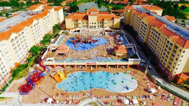 Un resort con varias piscinas, parque acuático y un edificio central grande.