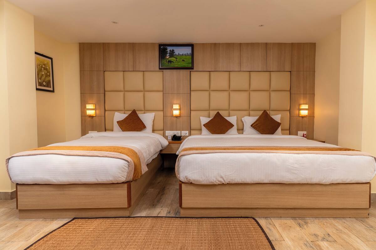 Une chambre d’hôtel avec deux lits, des têtes de lit en bois et des lampes fixées au mur.