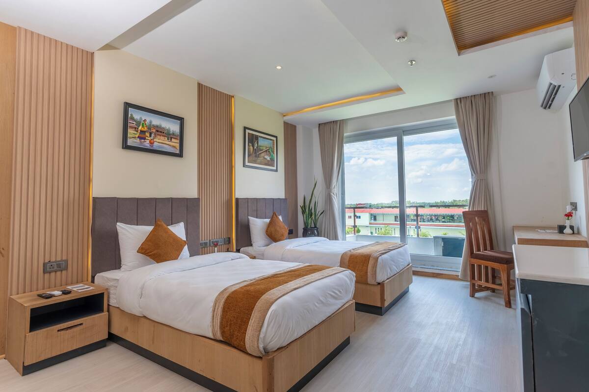 Une chambre d’hôtel avec deux lits, un bureau, une chaise et un téléviseur.