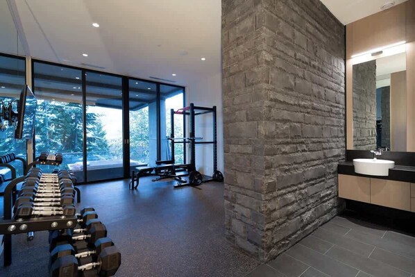 Une salle de sport moderne équipée d’un long banc, d’haltères et d’appareils de musculation.