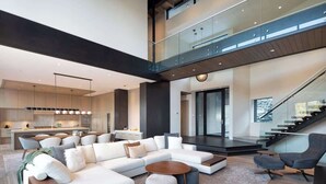 A modern living room with a sectional sofa, a coffee table, and a staircase leading to an upper level.