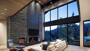 A modern living room with a stone fireplace, large windows, and a sectional sofa.