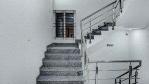 Una escalera con escalones de mármol y barandales de metal, que conduce a una habitación en el cuarto piso.