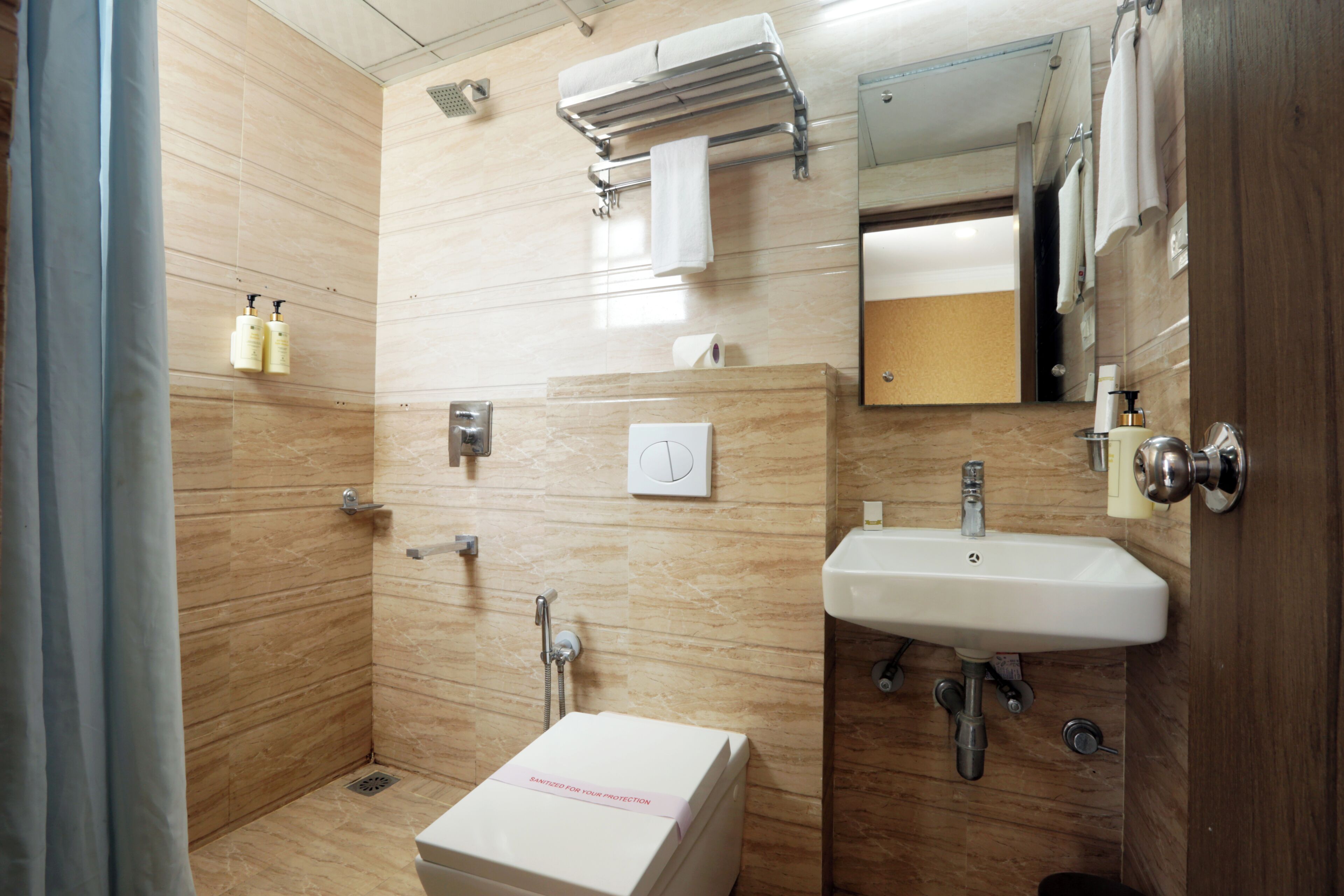 A bathroom with a shower, sink, towel rack, and a toilet.