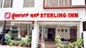 Exterior del Sterling Inn, con una entrada despejada, plantas en macetas al frente y un letrero visible.