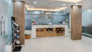 Un área de recepción de diseño moderno, con mostrador de recepción, ventilador de techo y separador de vidrio.