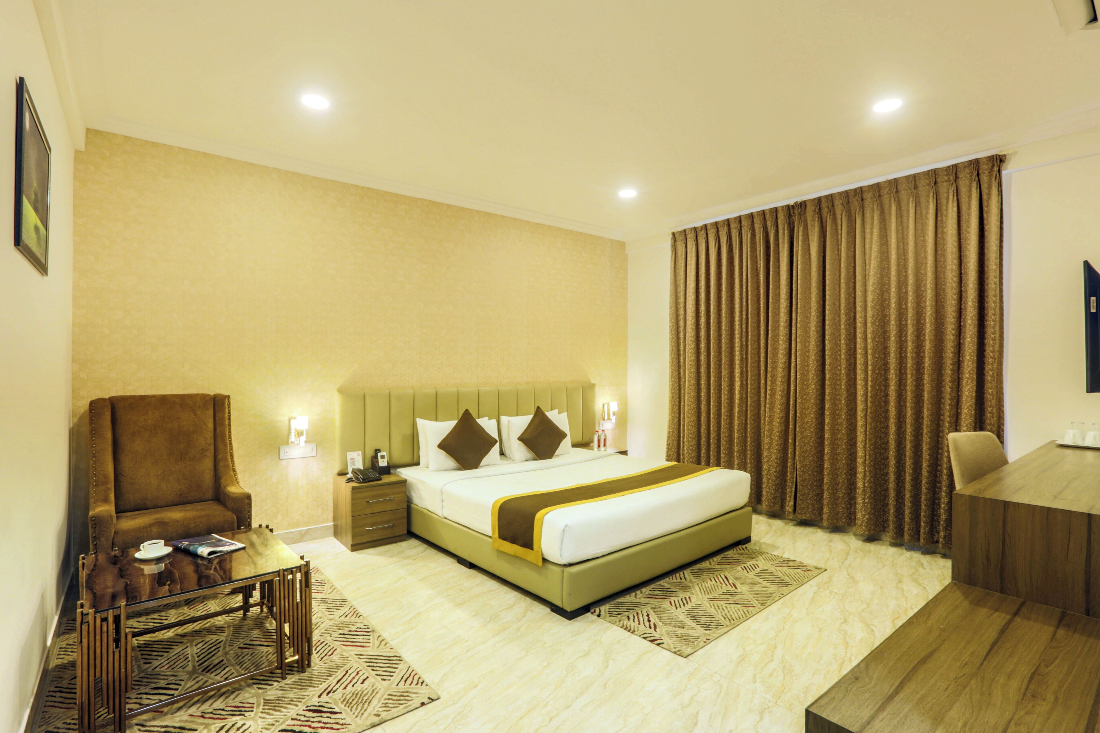 A hotel room with a bed, a chair, a desk, and a nightstand.