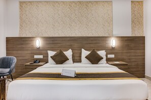 A hotel room with a large bed, two bedside tables, a chair, and a wall with a textured pattern. - ECKO Sterling Inn Near Bangalore International Airport (Devanahalli)