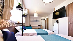 Een hotelkamer met twee bedden, een televisie, een bureau en een kitchenette.