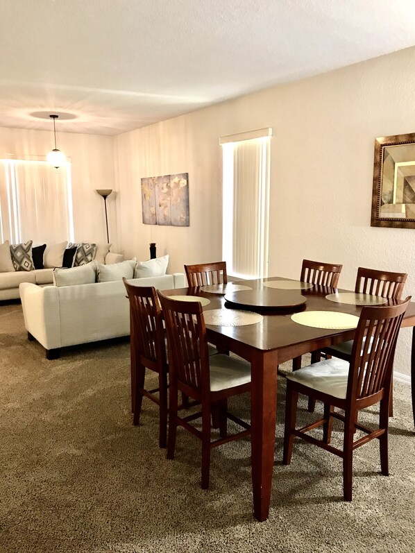 Un coin repas avec une table et des chaises en bois, un canapé blanc et un tableau accroché au mur.