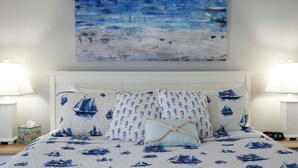 A bedroom with a bed featuring a nautical theme, a large abstract painting above the bed, and two bedside lamps. - Pool & Beach Access: Villa on Hilton Head Island (Hilton Head Island)