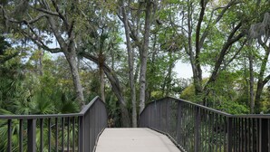 A bridge with metal railings and a concrete walkway surrounded by trees and greenery. - Pool & Beach Access: Villa on Hilton Head Island (Hilton Head Island)
