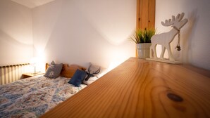 Een slaapkamer met een bed, kussens, een houten hoofdbord, een aan de muur bevestigde plant en een decoratie van een eland.